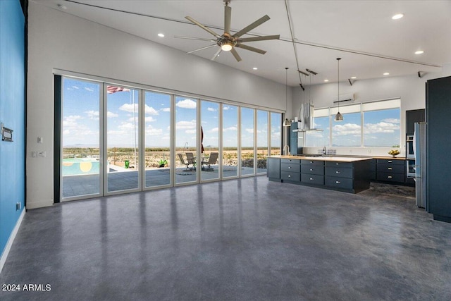 interior space featuring ceiling fan, hanging light fixtures, a high ceiling, and a center island