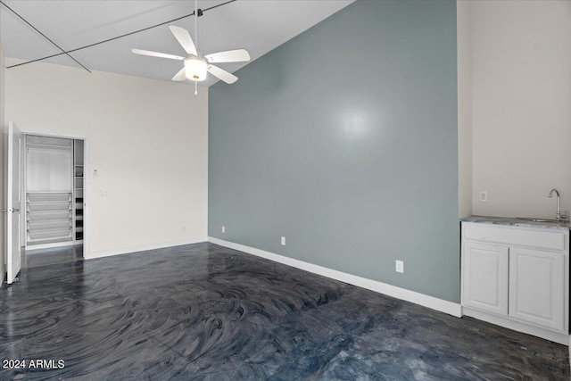unfurnished room with baseboards, concrete floors, a sink, and a ceiling fan