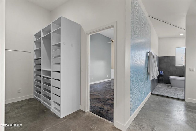 interior space featuring concrete flooring, baseboards, and a freestanding tub