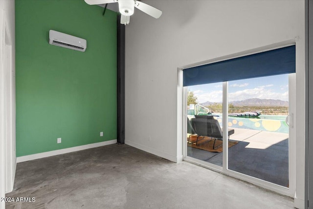 empty room featuring an AC wall unit, concrete floors, a mountain view, and ceiling fan