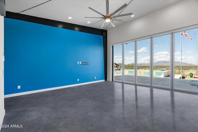empty room with baseboards, concrete floors, recessed lighting, a ceiling fan, and a mountain view