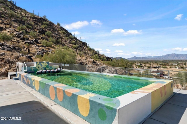 pool with a mountain view, fence, and a patio area