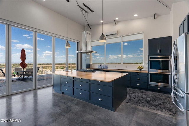 kitchen featuring island range hood, pendant lighting, stainless steel appliances, wooden counters, and a center island