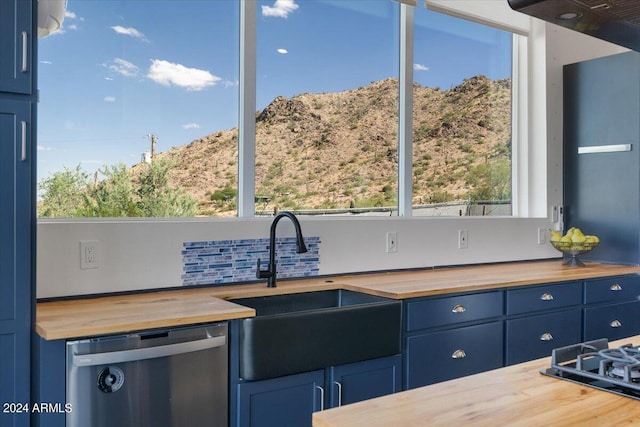 kitchen with blue cabinetry, dishwasher, sink, and wood counters