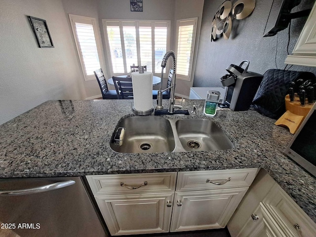 kitchen with dishwasher, stone countertops, white cabinets, and sink