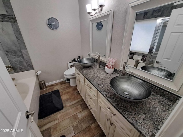 bathroom featuring a washtub, hardwood / wood-style floors, vanity, and toilet