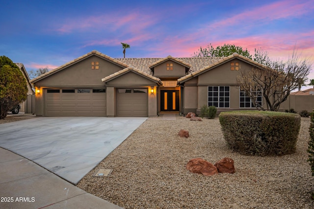 view of front of home featuring concrete driveway, a tiled roof, an attached garage, and stucco siding