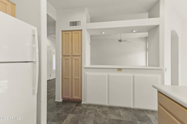 kitchen with a towering ceiling, white refrigerator, ceiling fan, and light brown cabinets