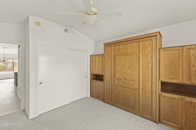 unfurnished bedroom featuring lofted ceiling, a closet, ceiling fan, and light carpet