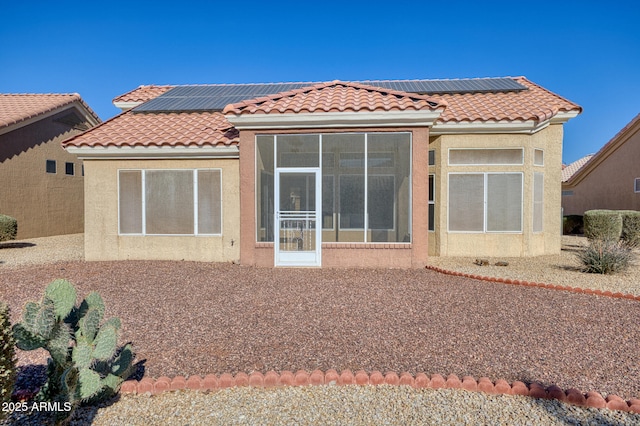 rear view of property with a sunroom and solar panels