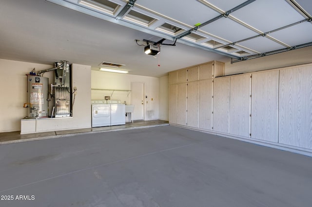 garage featuring a garage door opener, water heater, and washing machine and clothes dryer