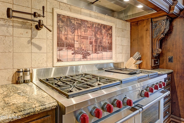 kitchen featuring light stone counters, high end stainless steel range oven, and tasteful backsplash