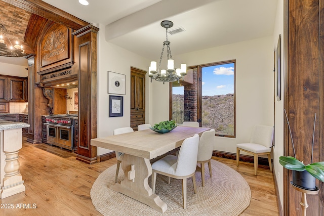 dining area with light wood-style flooring, visible vents, a chandelier, and baseboards