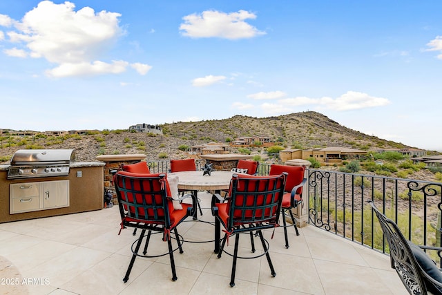 view of patio / terrace featuring outdoor dining space, a mountain view, an outdoor kitchen, and area for grilling