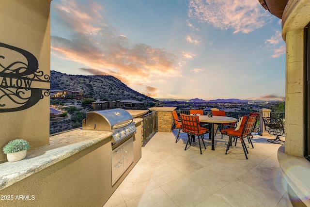 view of patio / terrace featuring outdoor dining space, a mountain view, and area for grilling