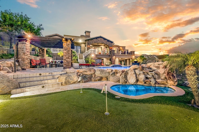 back of property featuring a balcony, stairs, an outdoor pool, and a patio