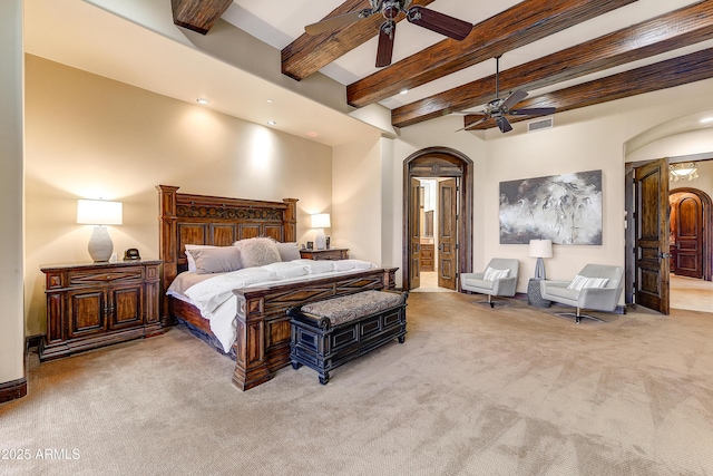 bedroom with arched walkways, ensuite bathroom, carpet flooring, visible vents, and beam ceiling