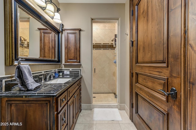 bathroom with a stall shower, vanity, baseboards, and tile patterned floors