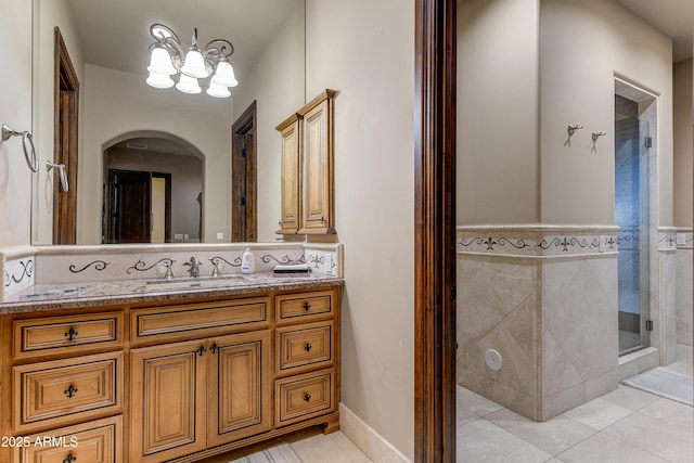 full bath with a notable chandelier, a shower stall, vanity, and tile patterned floors