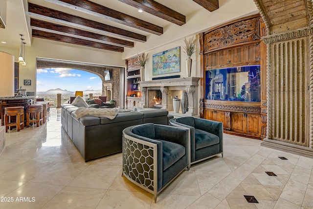 living area featuring a warm lit fireplace, light tile patterned floors, and beam ceiling