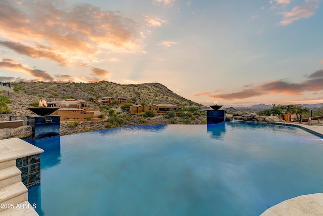 pool at dusk featuring a mountain view