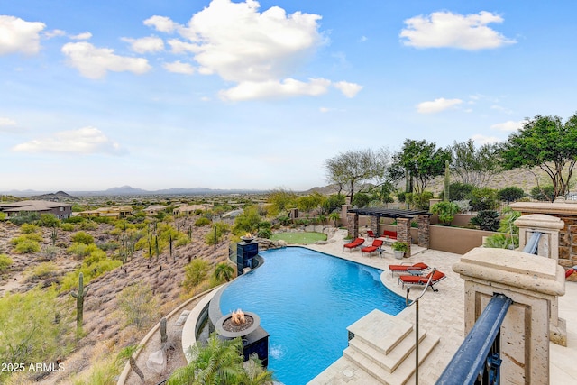 pool with an outdoor fire pit, a patio area, and a mountain view