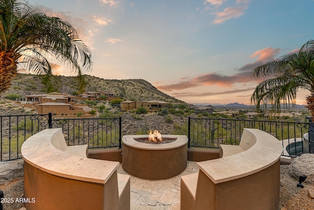 balcony at dusk featuring a mountain view and a fire pit