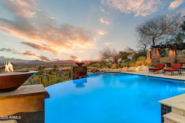 view of pool featuring an infinity pool, a patio area, a fire pit, and a mountain view