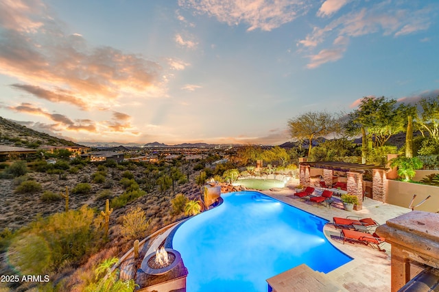 outdoor pool featuring a patio area, a mountain view, and a fire pit