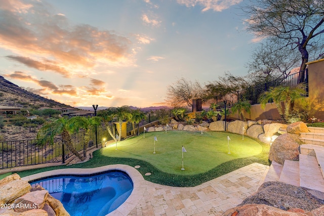 pool at dusk with a fenced backyard