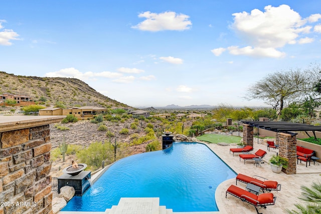 view of pool featuring an infinity pool, an outdoor fire pit, a patio area, and a mountain view