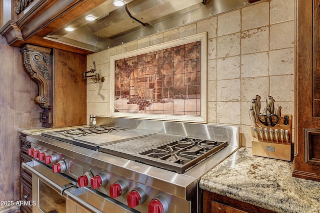 kitchen with range with two ovens, backsplash, and light stone counters