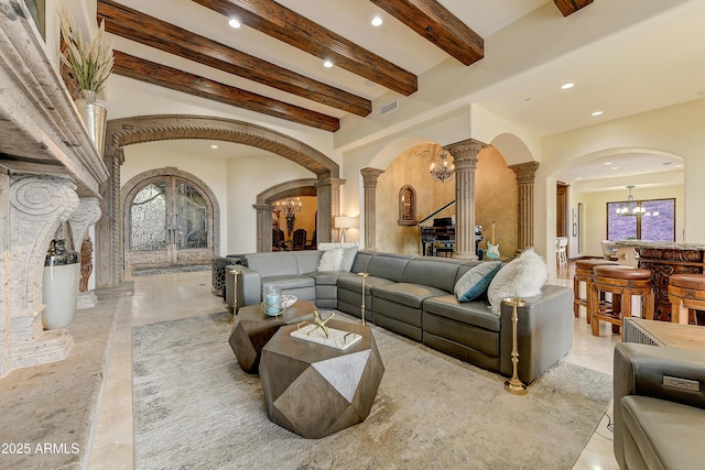 living room featuring decorative columns, arched walkways, a notable chandelier, and recessed lighting