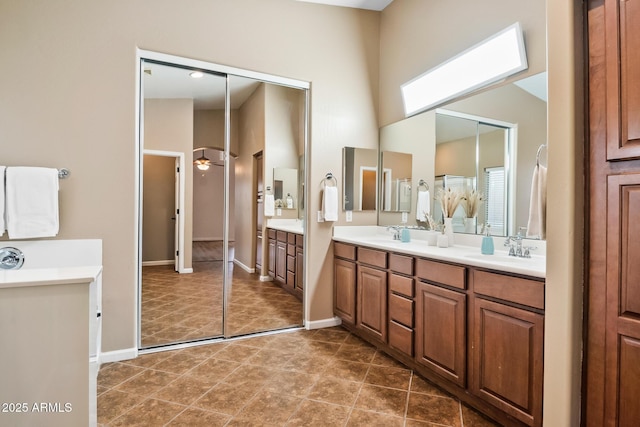 bathroom with tile patterned flooring, vanity, ceiling fan, and a skylight