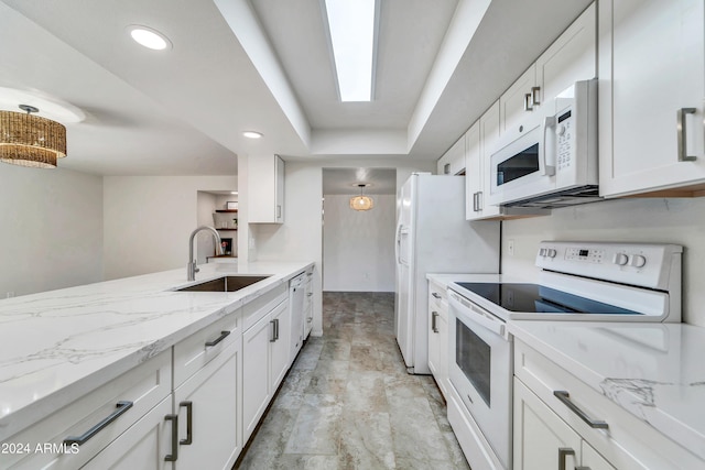 kitchen with white appliances, white cabinets, light stone counters, a sink, and recessed lighting