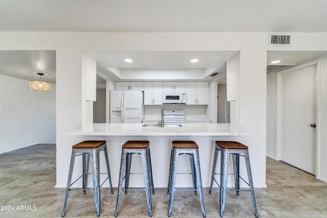 kitchen featuring visible vents, white appliances, white cabinetry, and a peninsula