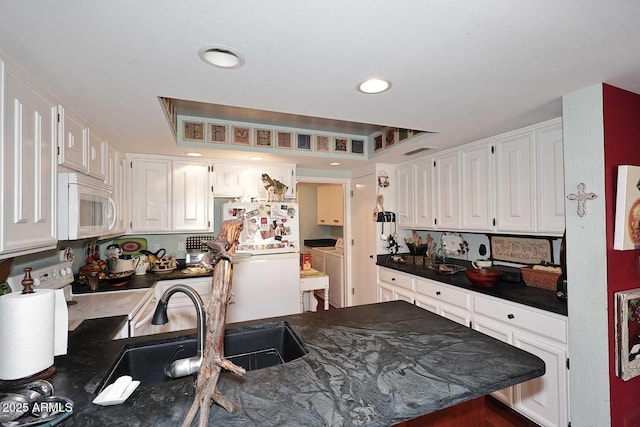 4317 N 70th St, Scottsdale, AZ 85251 - kitchen with white appliances, independent washer and dryer, dark countertops, white cabinetry, and recessed lighting