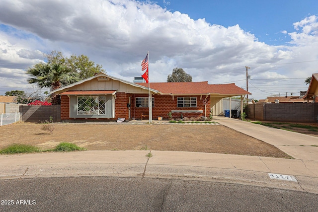 single story home featuring an attached carport, brick siding, fence, and driveway