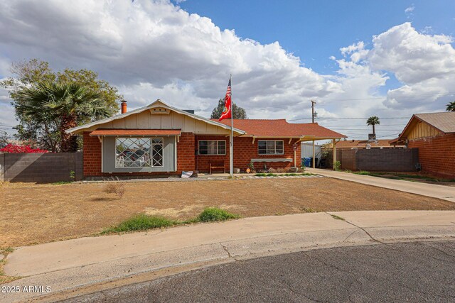 ranch-style home featuring brick siding, fence, concrete driveway, and a carport