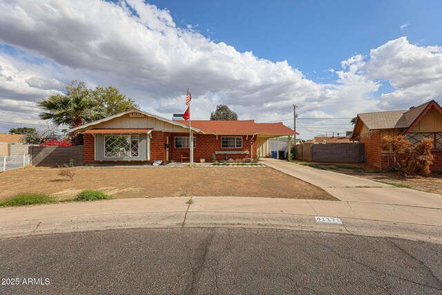 ranch-style home featuring an attached carport, driveway, fence, and brick siding