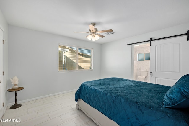 bedroom featuring a barn door, ensuite bathroom, light tile flooring, and ceiling fan