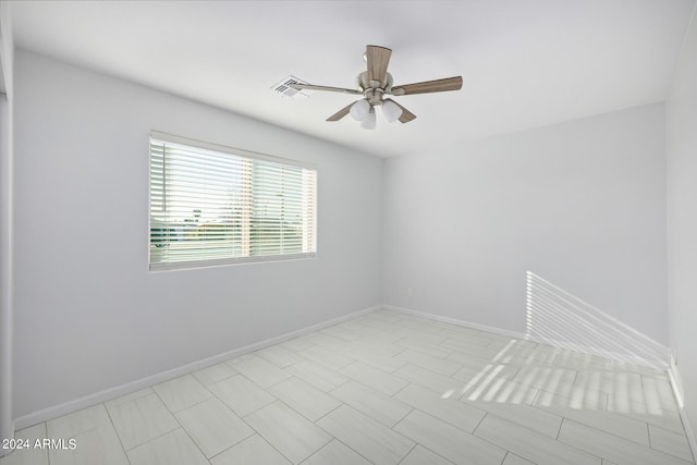 tiled empty room featuring ceiling fan