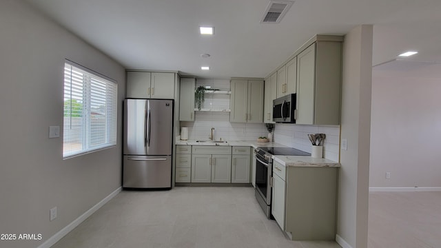 kitchen with stainless steel appliances, a sink, gray cabinetry, backsplash, and baseboards