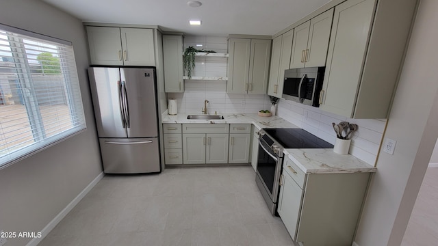 kitchen with appliances with stainless steel finishes, gray cabinets, a sink, and decorative backsplash