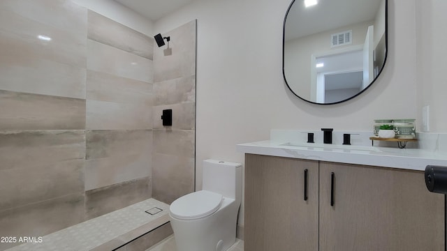 full bathroom featuring tiled shower, toilet, and vanity