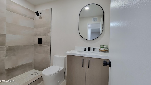 bathroom featuring toilet, vanity, and tiled shower