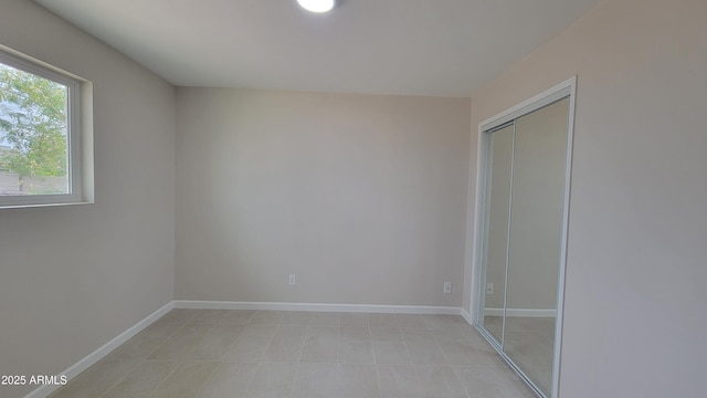 spare room with light tile patterned flooring and baseboards