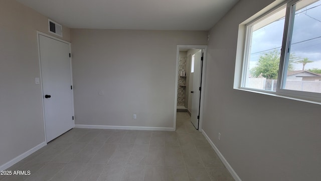 spare room with light tile patterned flooring and baseboards