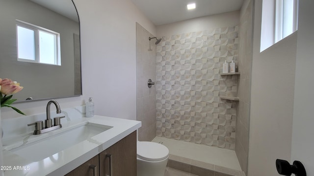 full bath featuring toilet, a tile shower, and vanity