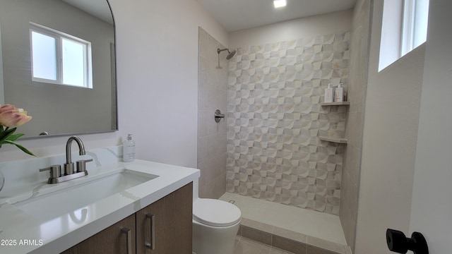 full bathroom featuring toilet, tiled shower, and vanity